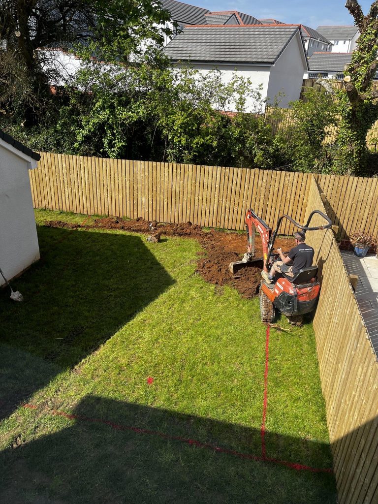 a man in a backhoe digging a hole in a yard