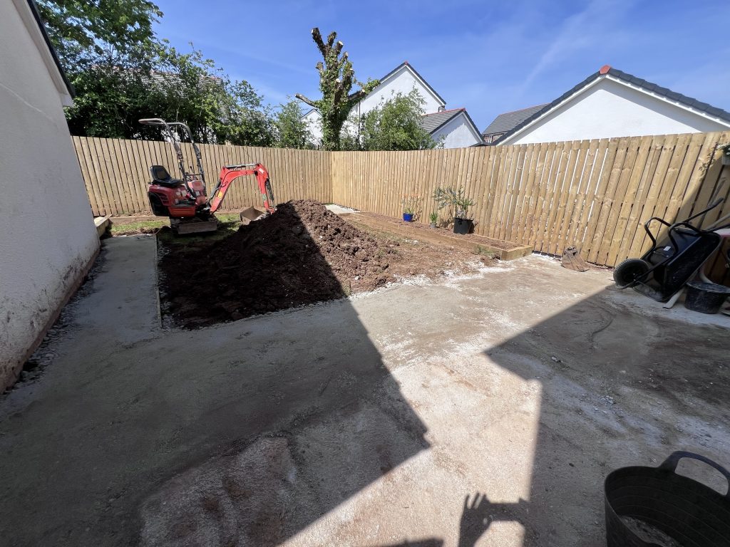 a back yard with a dirt pile and a fence